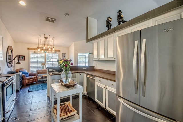 kitchen with pendant lighting, stainless steel appliances, white cabinets, dark tile patterned flooring, and kitchen peninsula