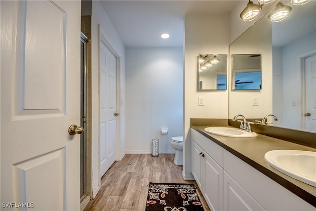 bathroom with hardwood / wood-style flooring, vanity, toilet, and a shower with shower door