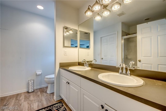 bathroom with vanity, hardwood / wood-style floors, a shower with door, and toilet