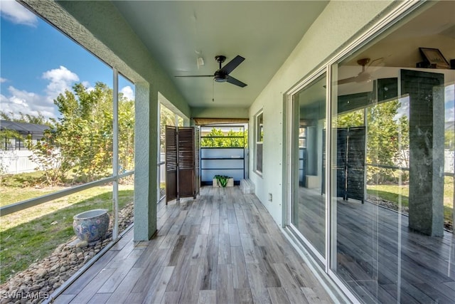 unfurnished sunroom with ceiling fan