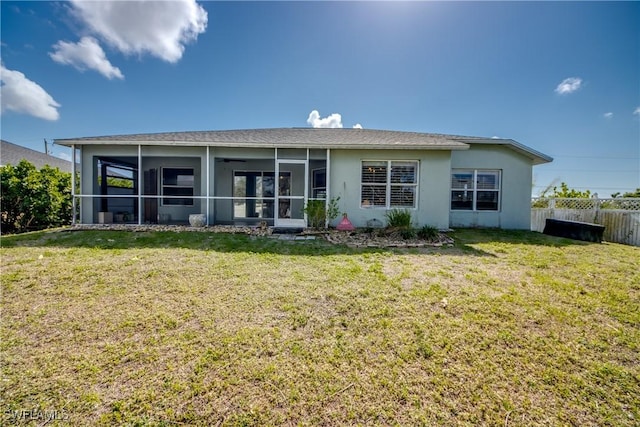 back of property with a sunroom and a lawn