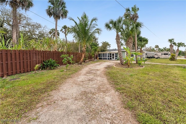 view of front of property featuring a front yard, fence, and dirt driveway