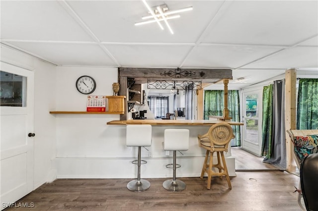 kitchen featuring a peninsula, a breakfast bar area, plenty of natural light, and wood finished floors