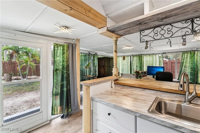 kitchen featuring a sink, white cabinetry, open floor plan, light countertops, and light wood-type flooring