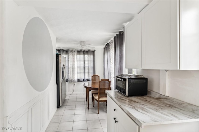 kitchen with a toaster, stainless steel refrigerator with ice dispenser, light tile patterned floors, light countertops, and white cabinets