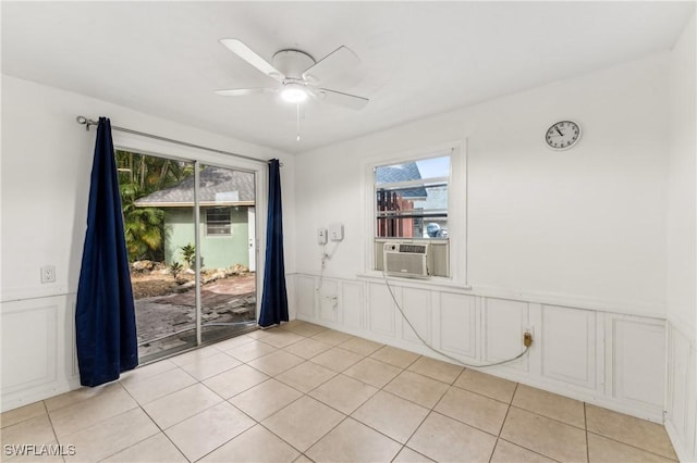 spare room featuring cooling unit, a wainscoted wall, ceiling fan, and light tile patterned floors