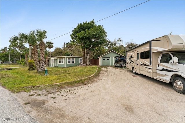 view of front of property with a detached garage, an outdoor structure, driveway, and a front lawn