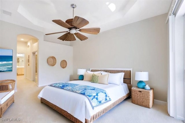 bedroom featuring ensuite bathroom, carpet flooring, ceiling fan, and a tray ceiling