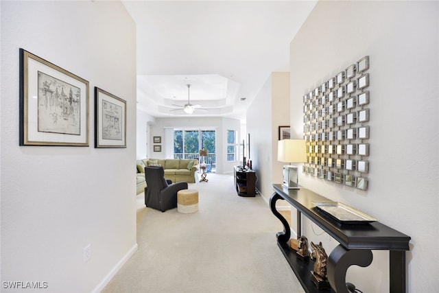 hallway with a raised ceiling and carpet flooring