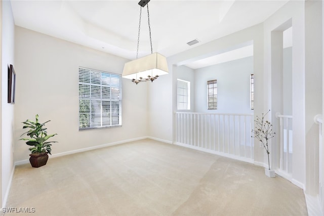 carpeted empty room with a notable chandelier