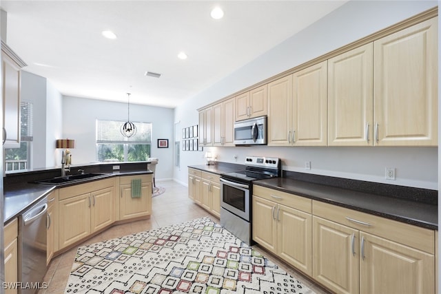 kitchen with hanging light fixtures, light tile patterned floors, stainless steel appliances, and sink