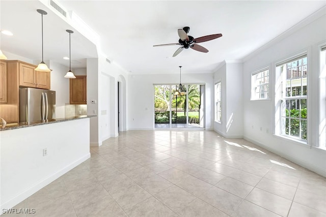 unfurnished living room with ornamental molding, ceiling fan with notable chandelier, and light tile patterned floors