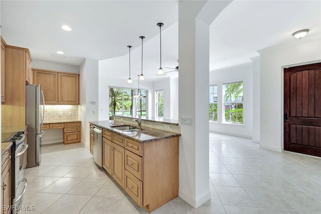 kitchen with sink, decorative light fixtures, dark stone countertops, appliances with stainless steel finishes, and decorative backsplash