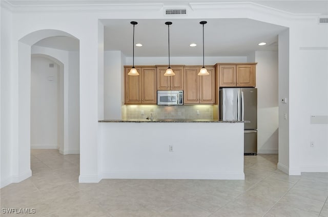 kitchen with crown molding, hanging light fixtures, dark stone counters, stainless steel appliances, and decorative backsplash