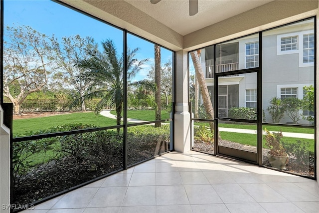 unfurnished sunroom featuring ceiling fan and a wealth of natural light