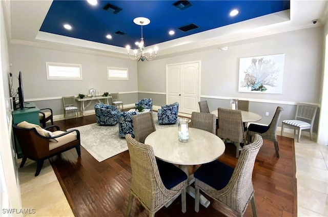 dining space featuring hardwood / wood-style floors, a notable chandelier, and a tray ceiling