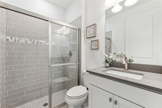 bathroom featuring vanity, a shower with door, and toilet