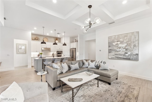 living room featuring coffered ceiling, sink, a chandelier, and beam ceiling