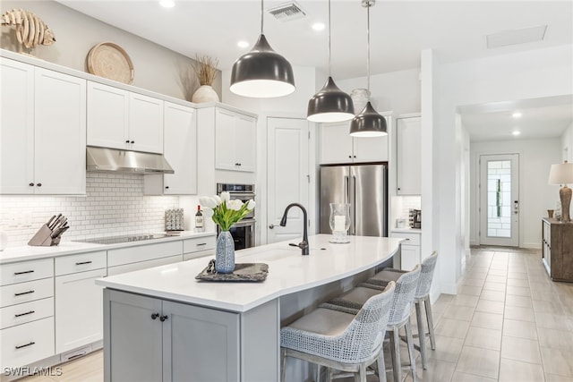 kitchen featuring sink, a breakfast bar area, appliances with stainless steel finishes, a kitchen island with sink, and white cabinetry