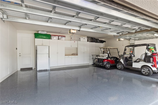 garage featuring white refrigerator and a garage door opener