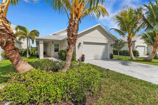 single story home with driveway, metal roof, an attached garage, a front lawn, and board and batten siding