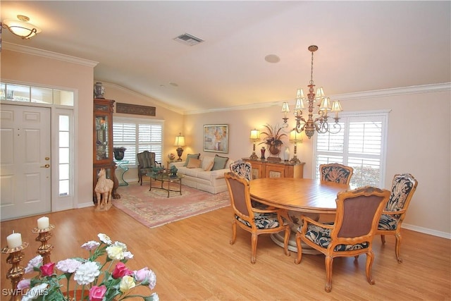 dining area with an inviting chandelier, ornamental molding, lofted ceiling, and light wood-type flooring