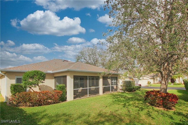 rear view of house with a yard and a sunroom