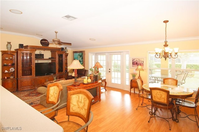 living room with ornamental molding, ceiling fan with notable chandelier, light hardwood / wood-style floors, and french doors