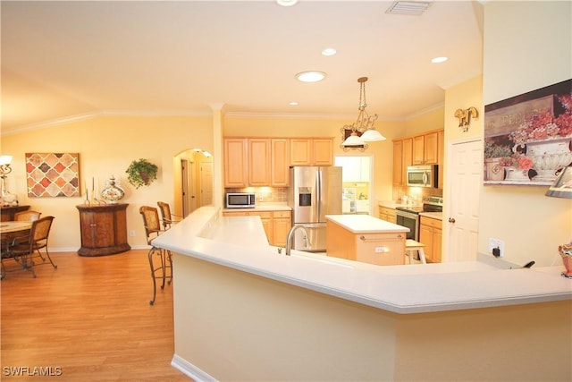 kitchen with decorative light fixtures, light brown cabinets, appliances with stainless steel finishes, kitchen peninsula, and a kitchen island