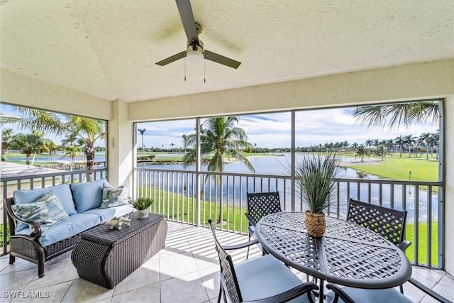 sunroom / solarium featuring ceiling fan and a water view