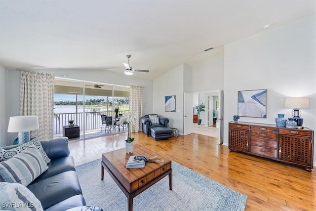 living area featuring a ceiling fan, visible vents, vaulted ceiling, and light wood finished floors