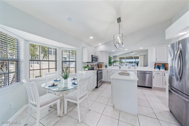 kitchen with a kitchen island, appliances with stainless steel finishes, light countertops, white cabinetry, and pendant lighting