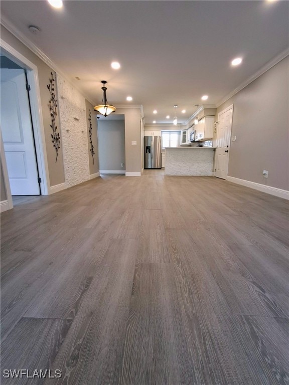 unfurnished living room with baseboards, ornamental molding, wood finished floors, and recessed lighting