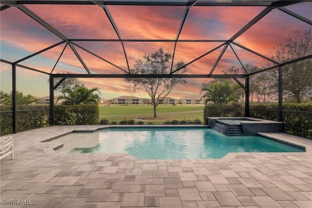 pool at dusk featuring an in ground hot tub, a patio, and glass enclosure