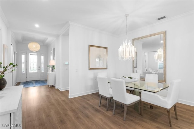 dining area featuring crown molding, dark wood finished floors, visible vents, and an inviting chandelier