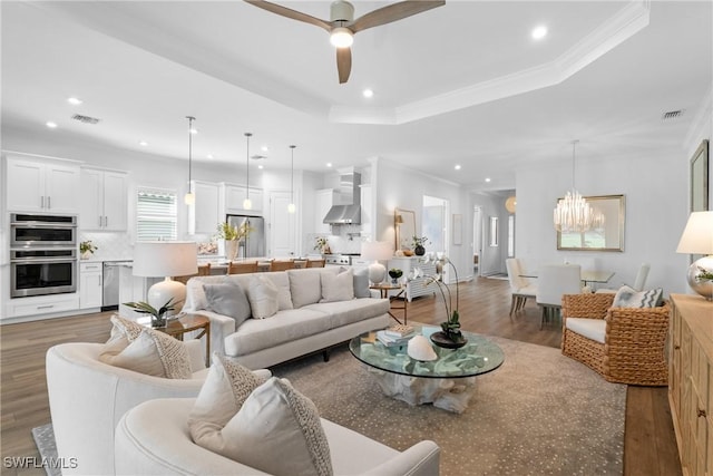 living room featuring ornamental molding, a raised ceiling, visible vents, and wood finished floors