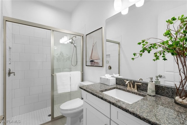 bathroom with a shower with door, vanity, and toilet