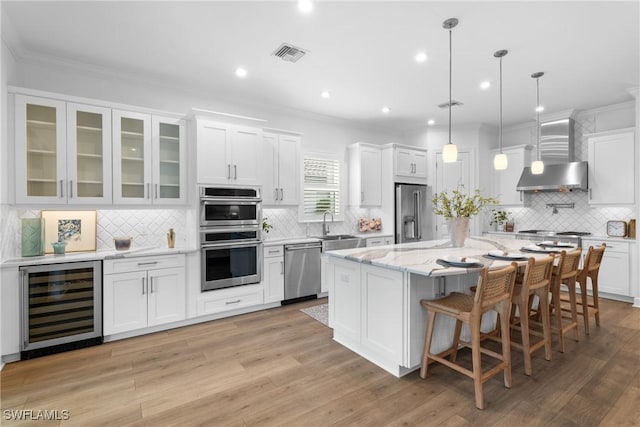 kitchen with white cabinets, beverage cooler, and wall chimney exhaust hood