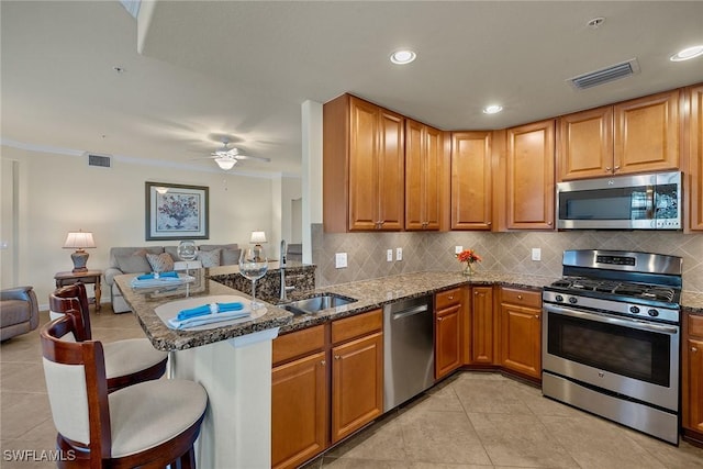 kitchen with visible vents, open floor plan, dark stone countertops, stainless steel appliances, and a sink