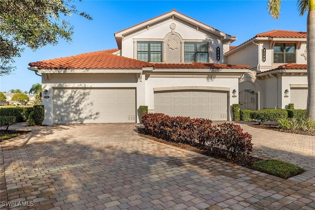 mediterranean / spanish house featuring a tiled roof, decorative driveway, and stucco siding