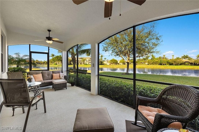 sunroom / solarium featuring a ceiling fan and a water view