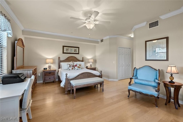 bedroom featuring baseboards, visible vents, crown molding, light wood-type flooring, and a closet