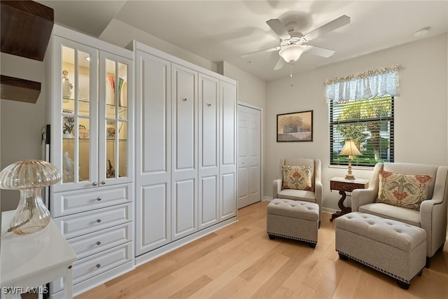 sitting room featuring light wood finished floors, a ceiling fan, and baseboards