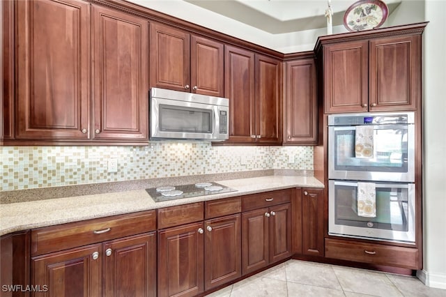 kitchen with light tile patterned floors, stainless steel appliances, light stone countertops, and backsplash