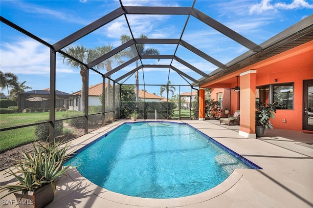 view of swimming pool featuring a patio, ceiling fan, and glass enclosure