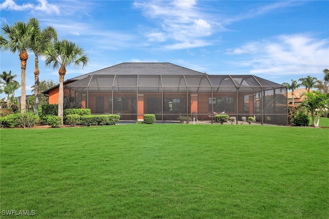 rear view of house featuring a lawn and glass enclosure