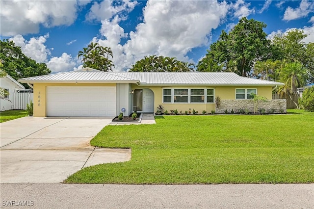 ranch-style house featuring stucco siding, a front yard, metal roof, a garage, and driveway