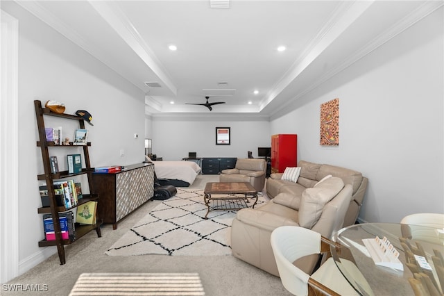 living room featuring light colored carpet, ornamental molding, a raised ceiling, and ceiling fan