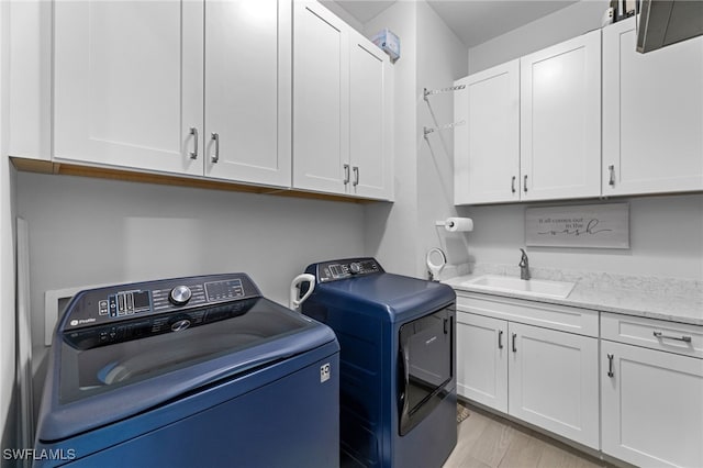 laundry room with light hardwood / wood-style floors, sink, cabinets, and washer and dryer