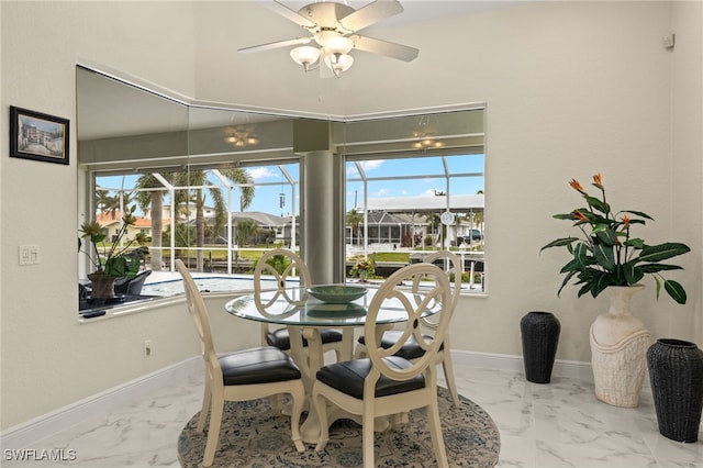 dining area with ceiling fan, marble finish floor, a wealth of natural light, and baseboards